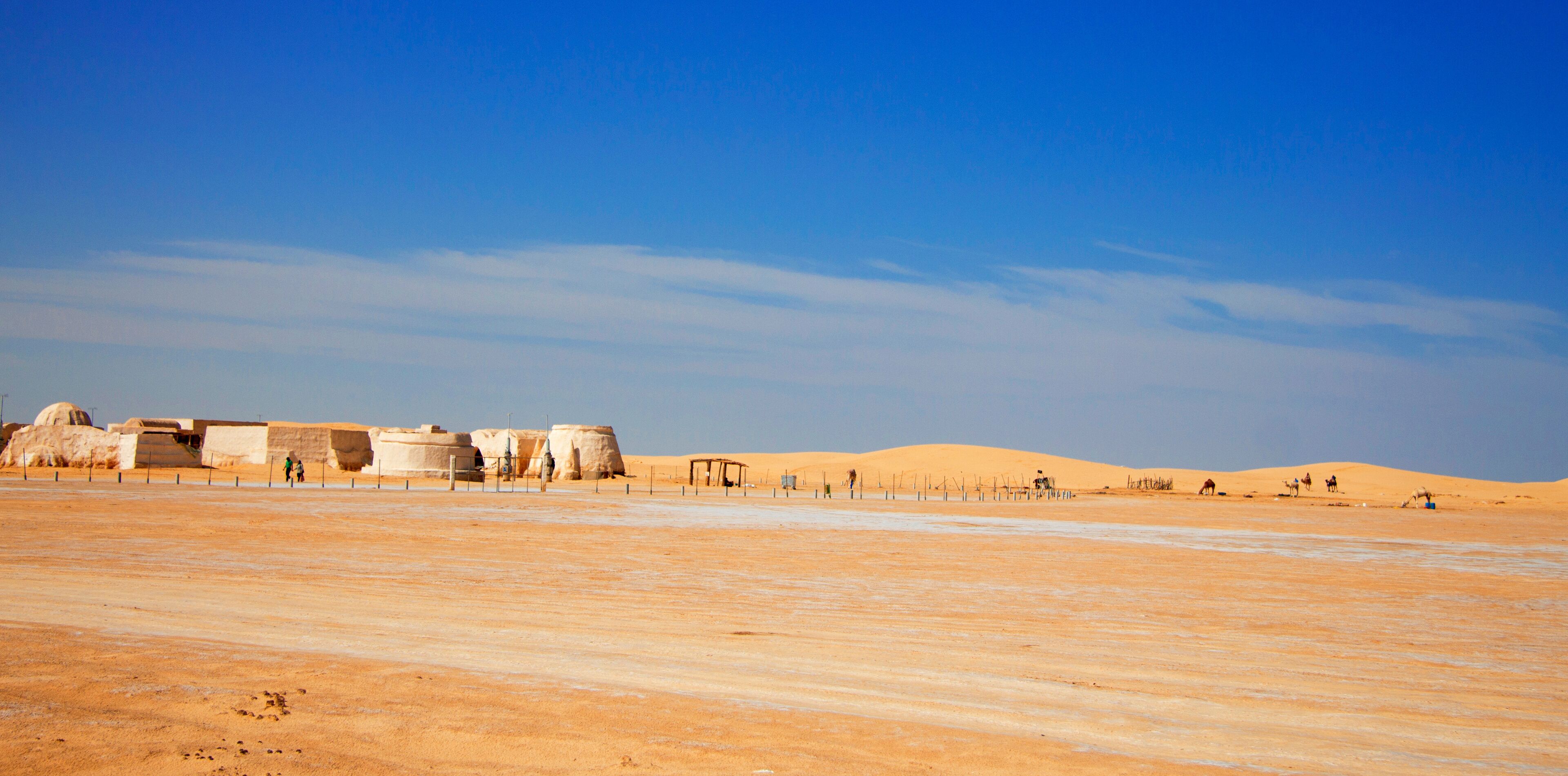 A desert landscape with sand dunes and ancient stone structures.