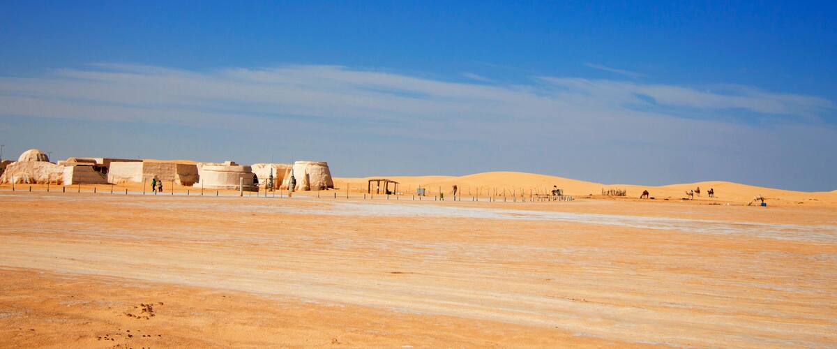 A desert landscape with sand dunes and ancient stone structures.