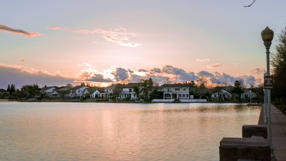 A lakeside residential area with houses and a lamp post.
