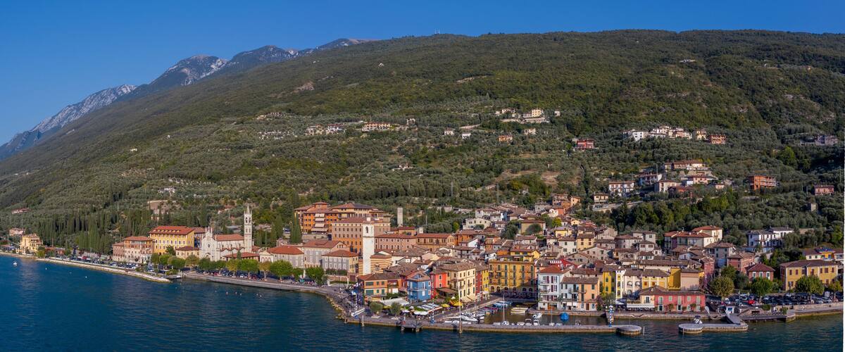 A coastal town with colorful buildings, a church, and a mountain backdrop.