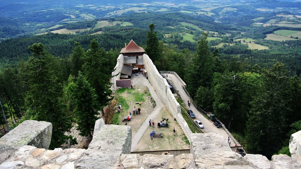 A stone fortification with a triangular roof overlooking a valley.