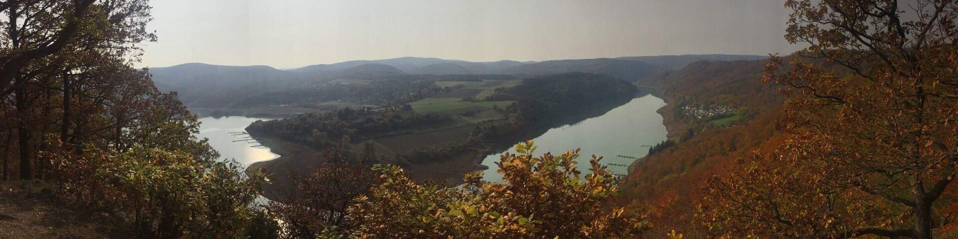 A valley with a river, surrounded by hills and autumn foliage.