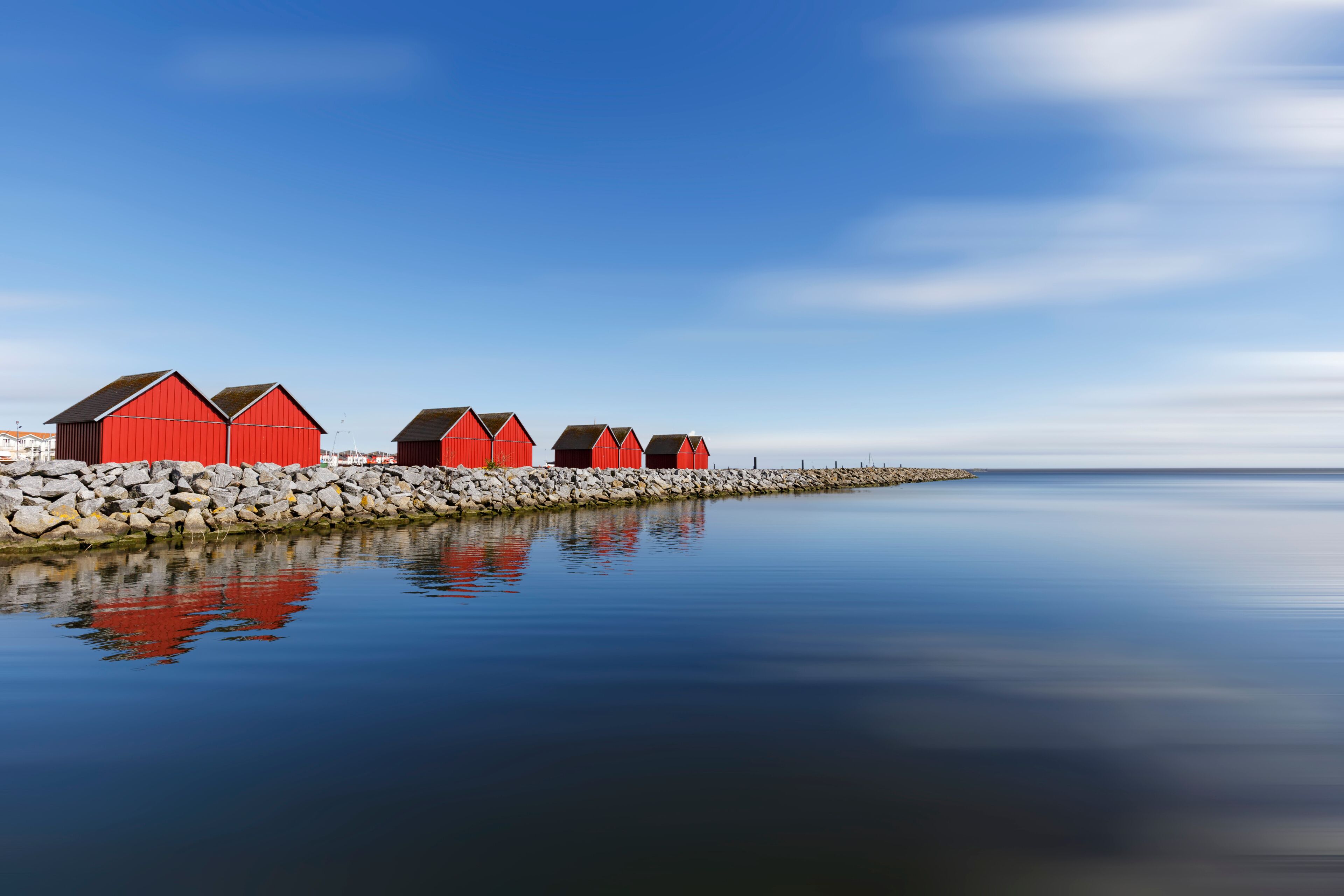 A row of red buildings by a calm body of water with a clear sky.