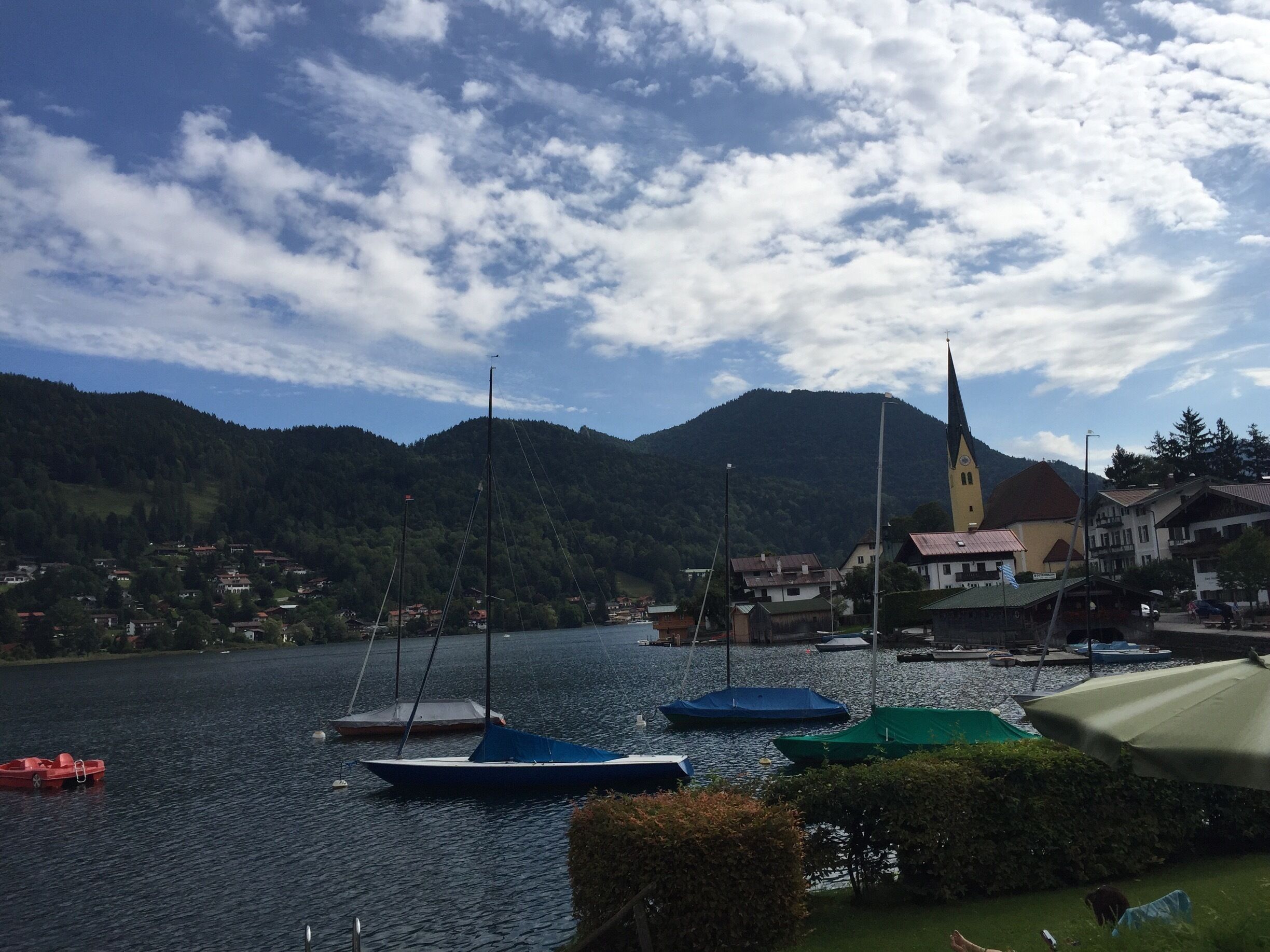 A lake with boats, a church, and houses in the background.