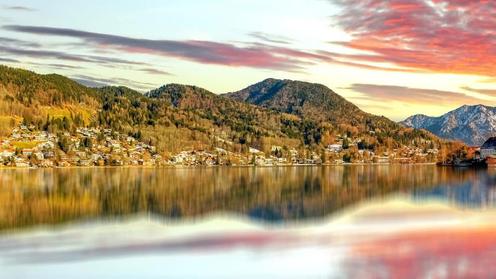 Un lac de montagne bordé d’un village, d’une église et entouré de sommets enneigés.