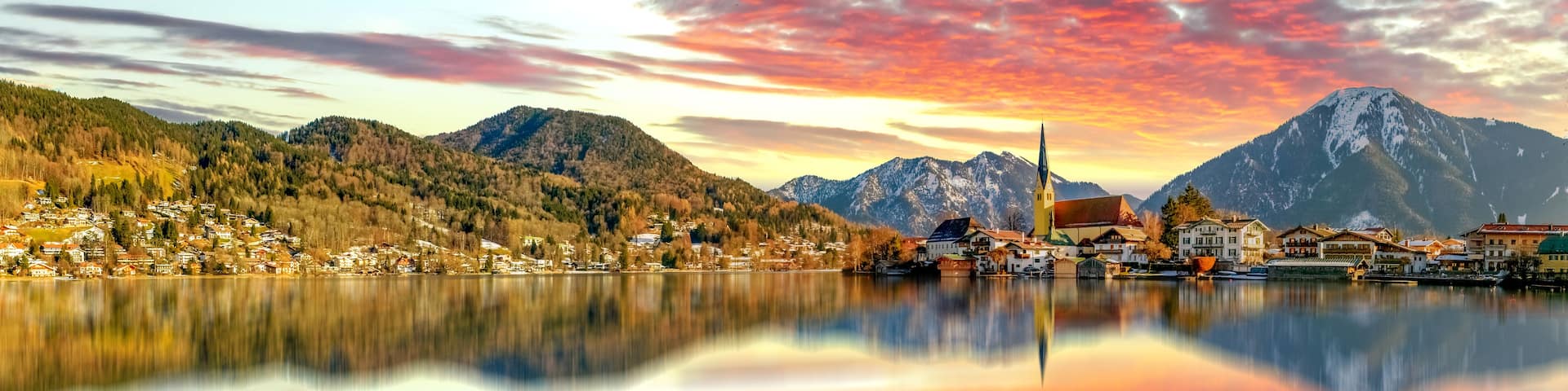 A mountain lake with a village, a church, and snow-capped peaks.