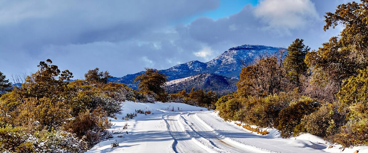 A snow-covered road with mountains in the background.