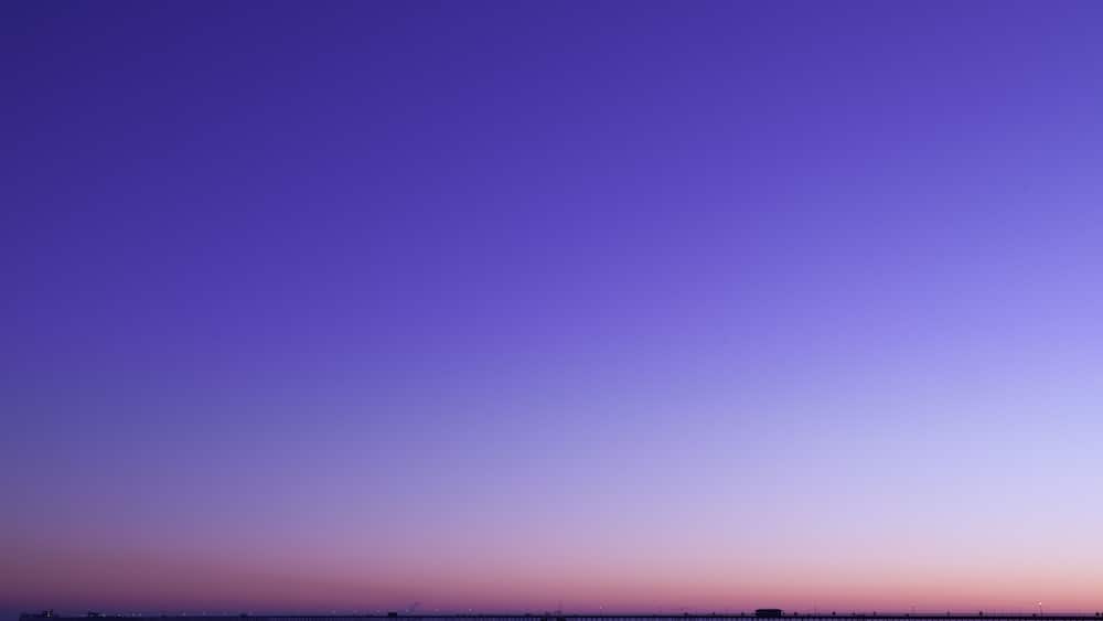 A beach at sunset with a pier extending into the water.