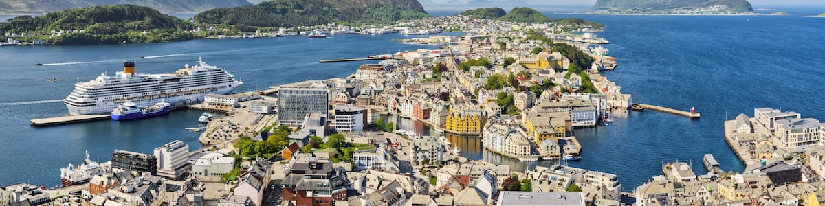 A coastal city with a cruise ship docked, surrounded by mountains and a harbor.