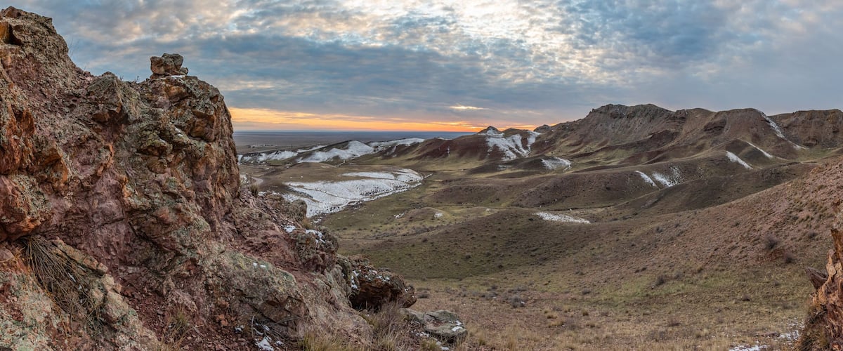 Rugged mountains with snow patches and a cloudy sky.