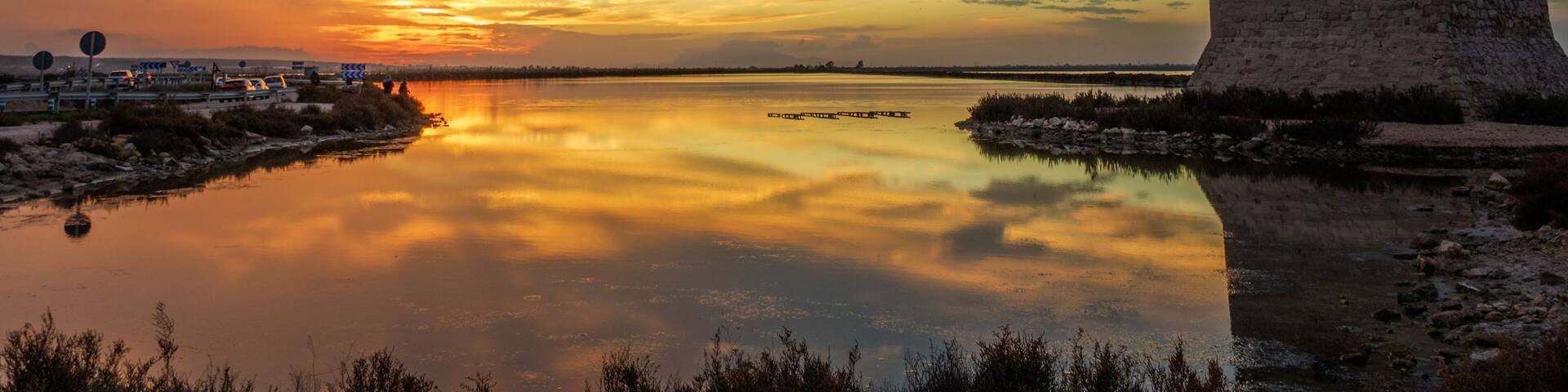 Sunset at Tamarit Tower (built in 16th century) and salt lagoons in Santa Pola, Alicante, Spain