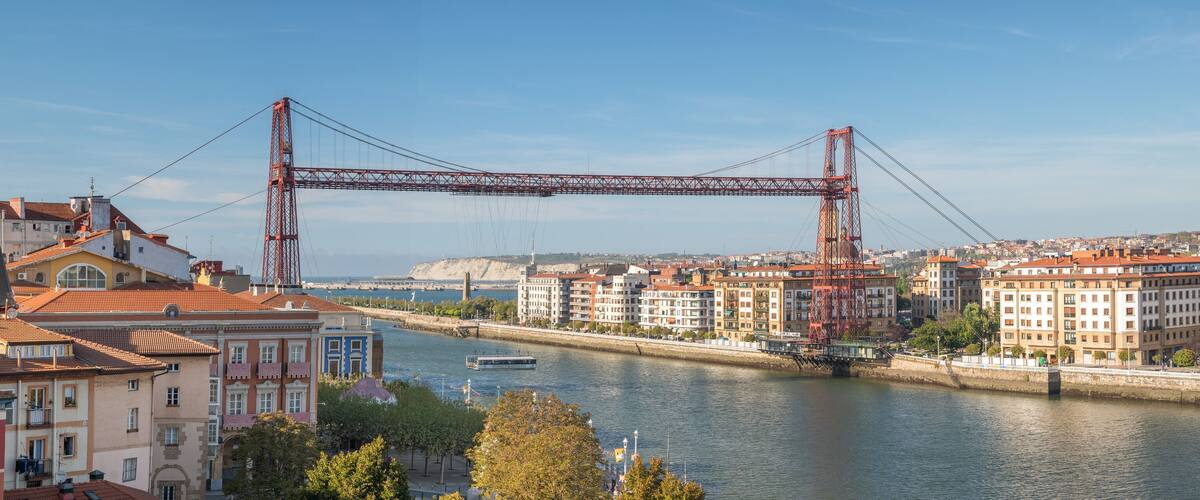 A river with a bridge, buildings, and a boat.