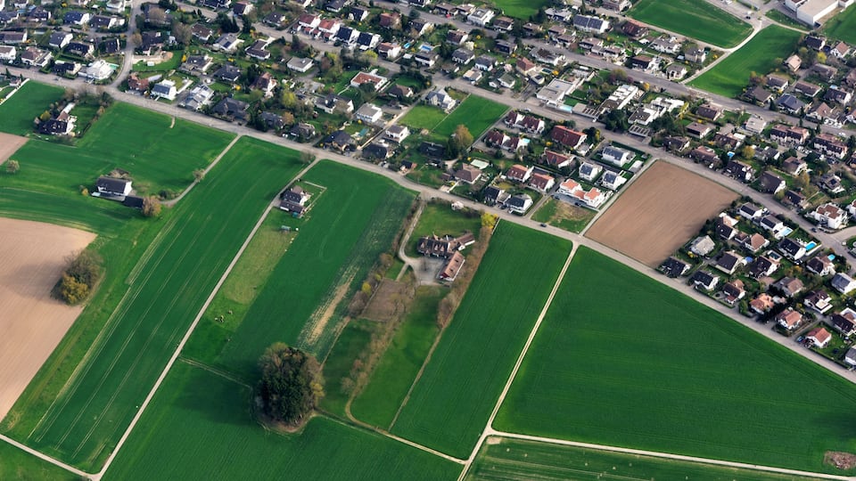 A residential area with houses, roads, and agricultural fields.