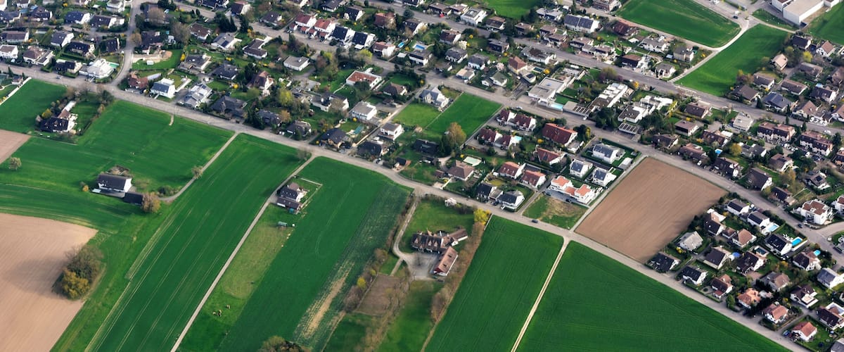 A residential area with houses, roads, and agricultural fields.