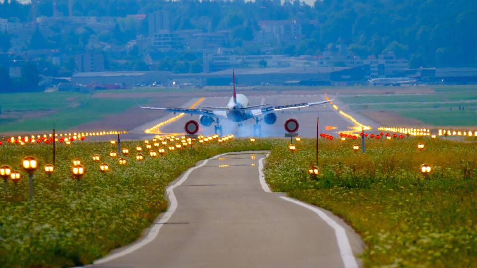 An airplane on the runway with a cityscape in the background.