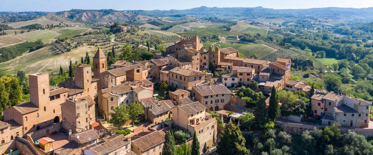 A historic town with medieval architecture, surrounded by rolling hills and vineyards.