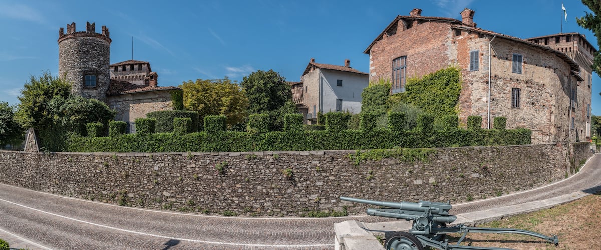 A cobblestone street, a historic stone tower, and a building with a brick facade.