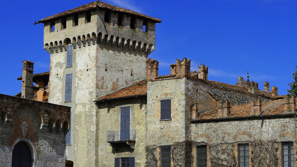 A historic stone building with a tower, arched windows, and a tiled roof.