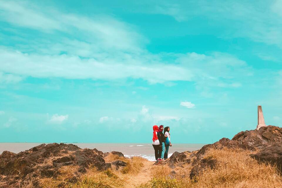 A coastal path with rocky terrain and a clear sky.