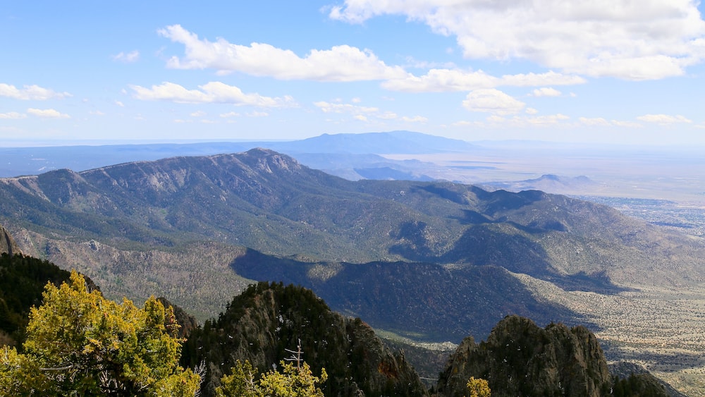 A mountainous landscape with dense forests and a clear sky.