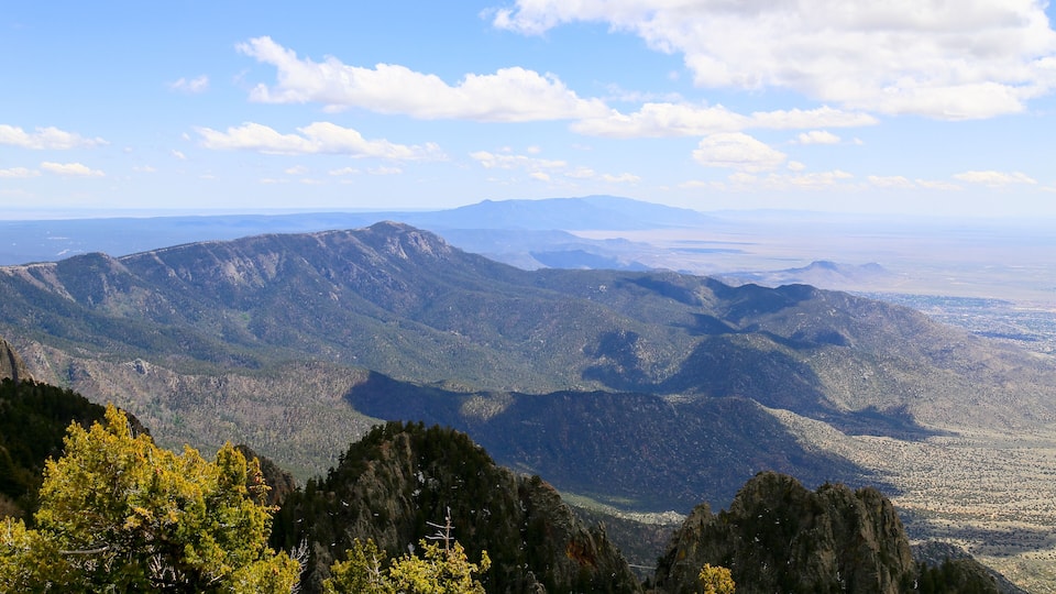 A mountainous landscape with dense forests and a clear sky.