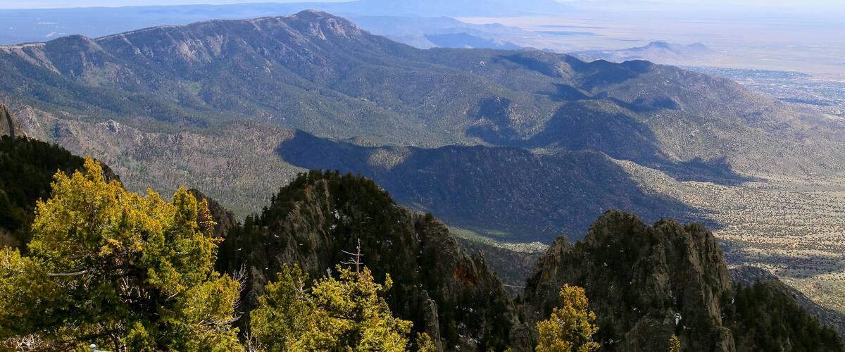 A mountainous landscape with dense forests and a clear sky.