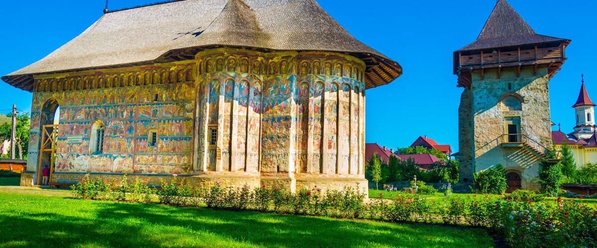 A historic building with colorful frescoes and a tower with a red roof.