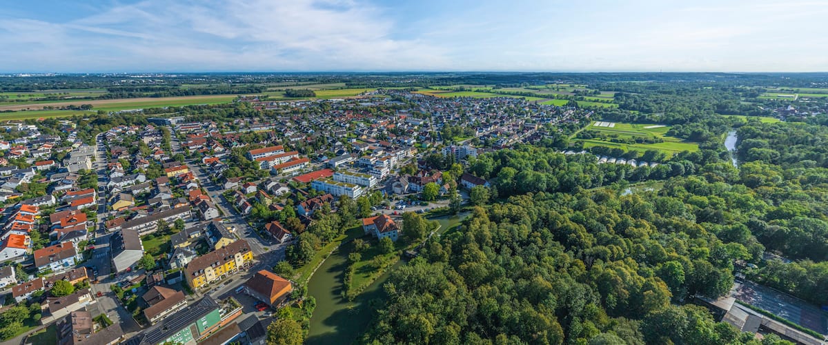 A town with dense housing, a river, and surrounding greenery.