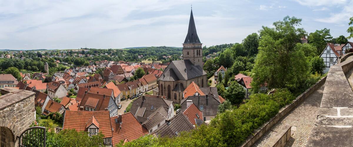 A historic town with red-tiled roofs, a prominent church tower, and a stone fortification.