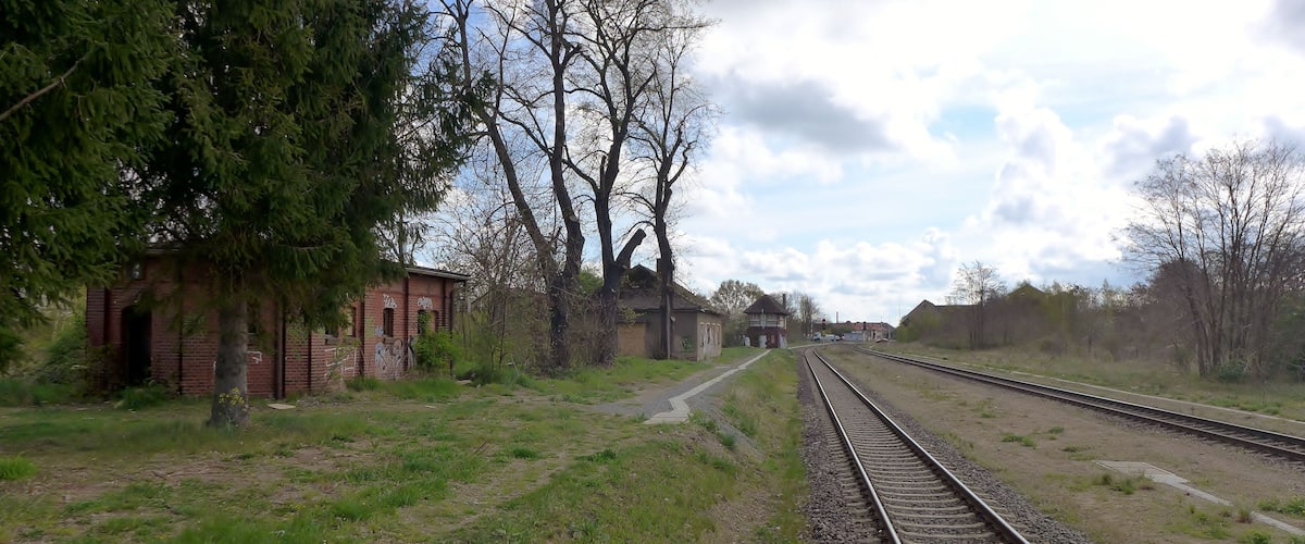 A railway track with a brick building and trees on the left.