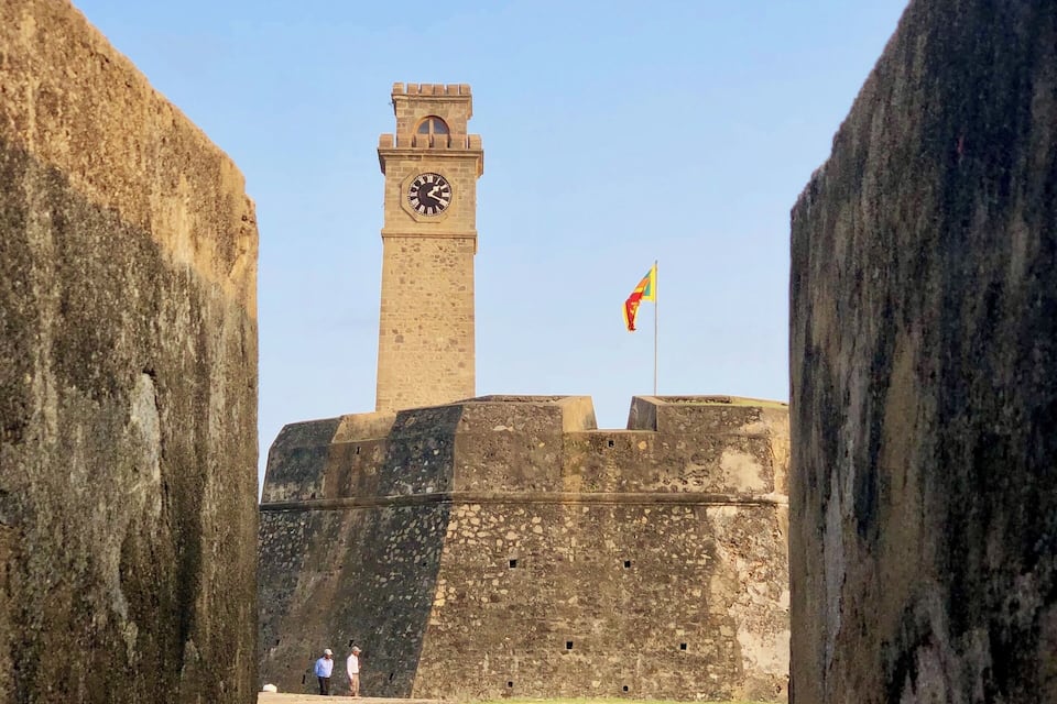 A historic fort with a clock tower and a flag.