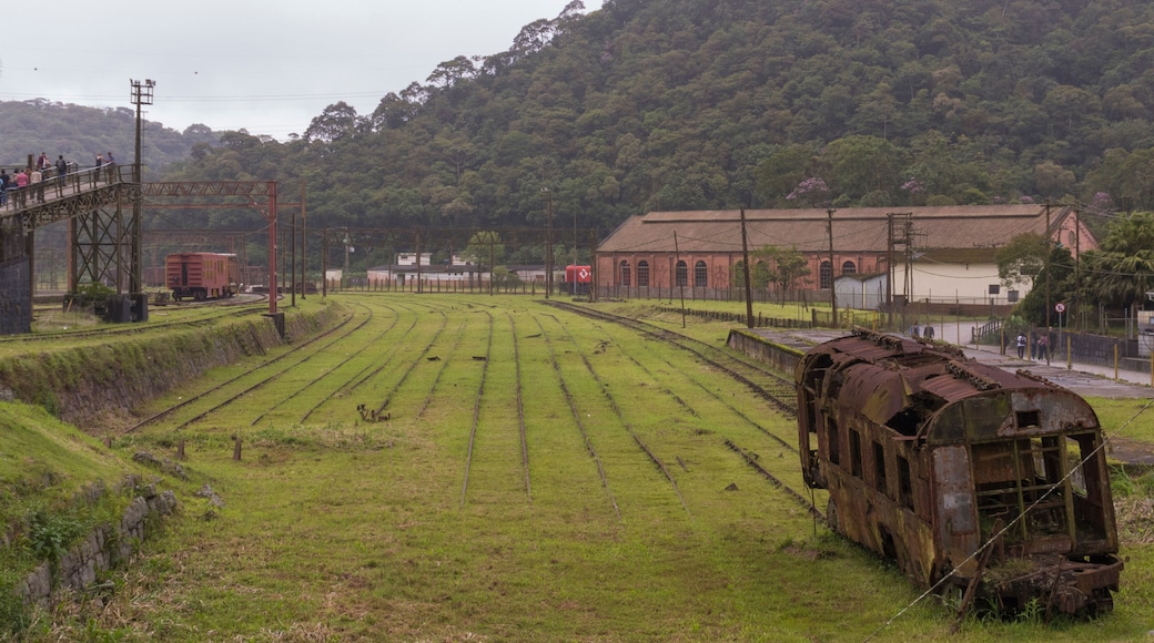 A railway yard with tracks, a rusted train car, and a building in the background.