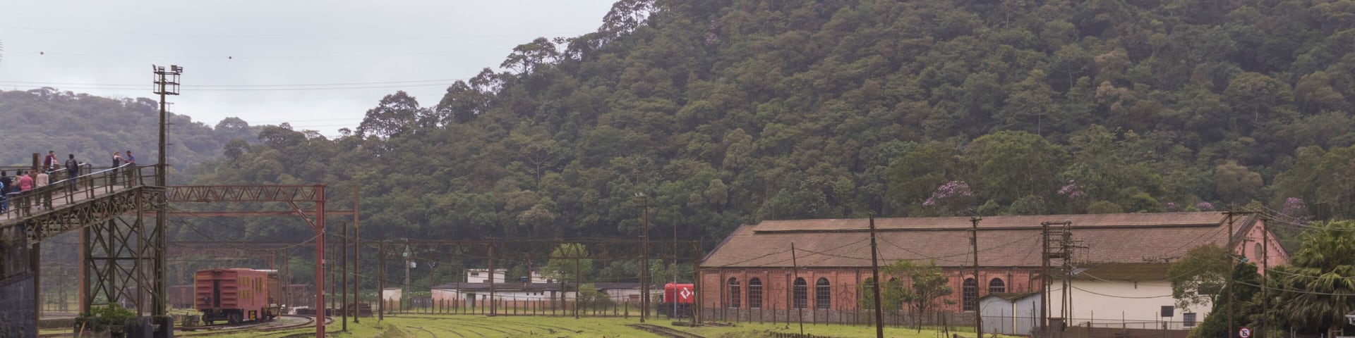 A railway yard with tracks, a rusted train car, and a building in the background.