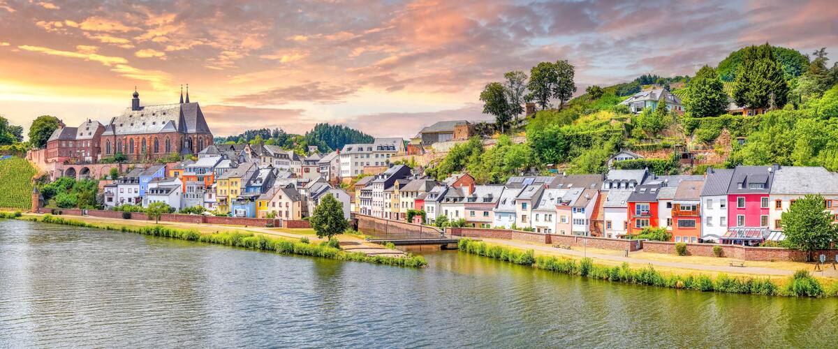 A river with a bridge, a historic building, and colorful houses along the banks.