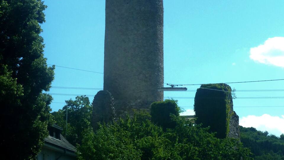 A tall stone tower with a conical roof, surrounded by lush greenery and a clear blue sky.