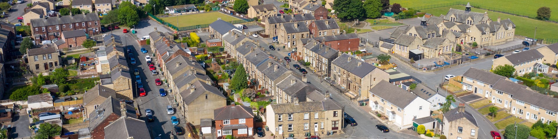 A residential area with houses, roads, and green fields.