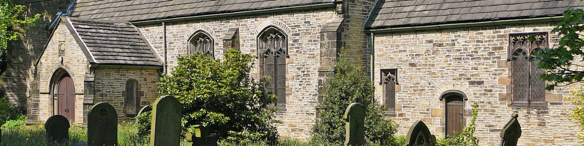 A historic church with a tower and multiple tombstones in the foreground.