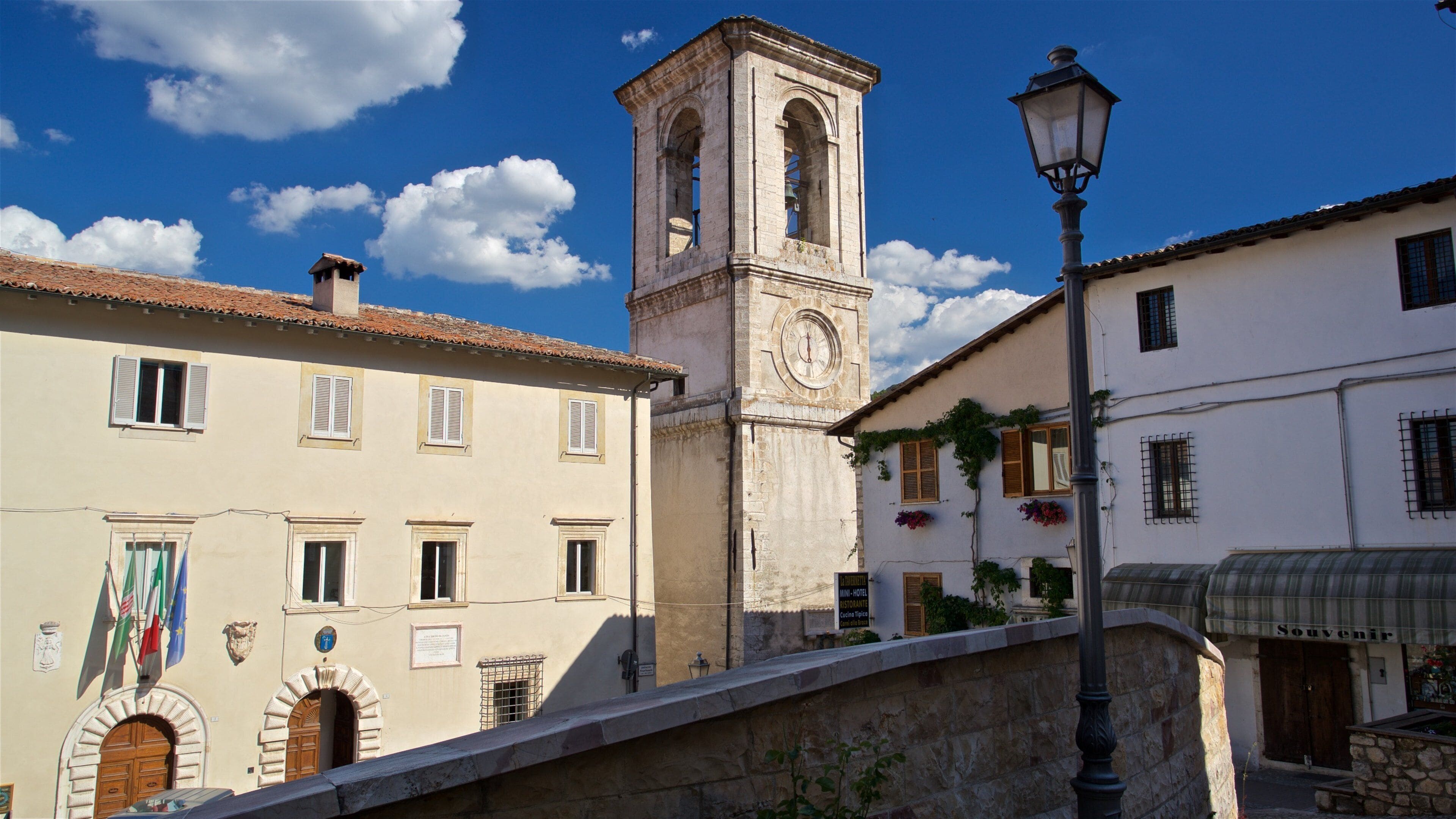 A historic town with a clock tower, a bridge, and traditional buildings.