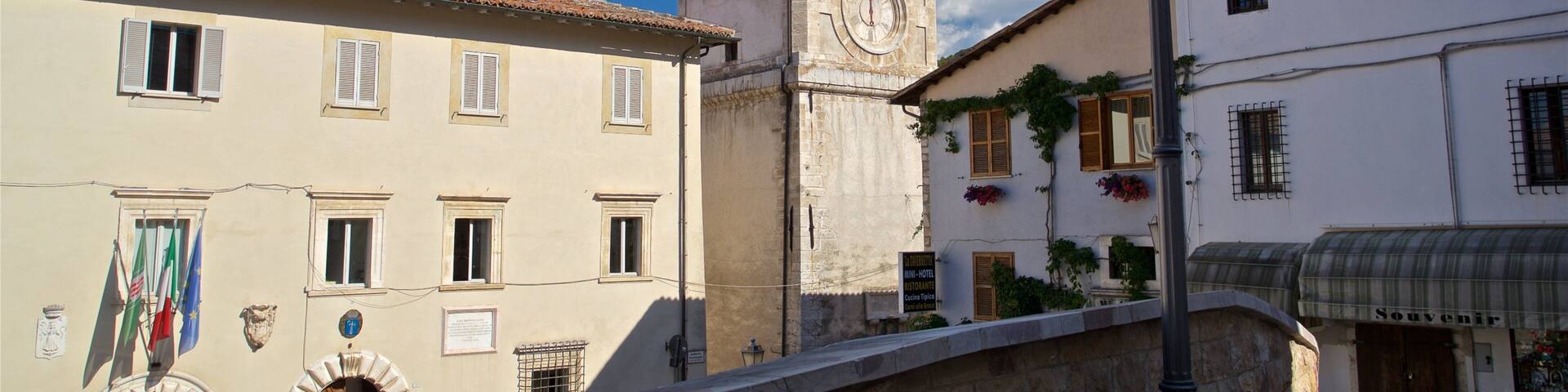 A historic town with a clock tower, a bridge, and traditional buildings.