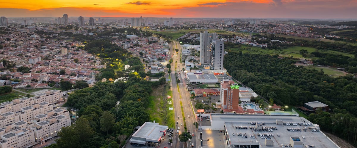 A cityscape at sunset with a prominent hotel, dense residential buildings, and a highway.