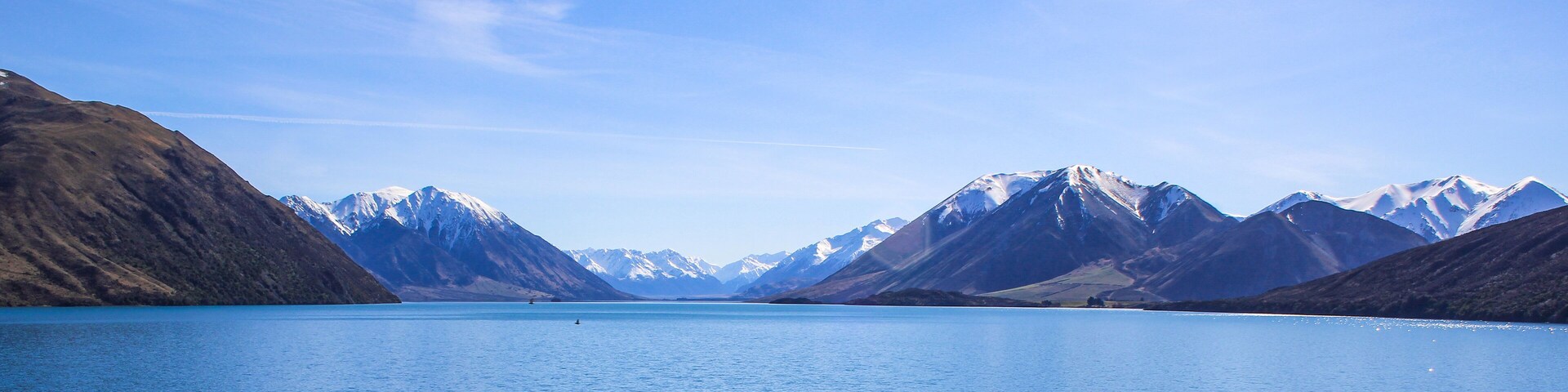 Un lago tranquilo rodeado de montañas nevadas bajo un cielo despejado.