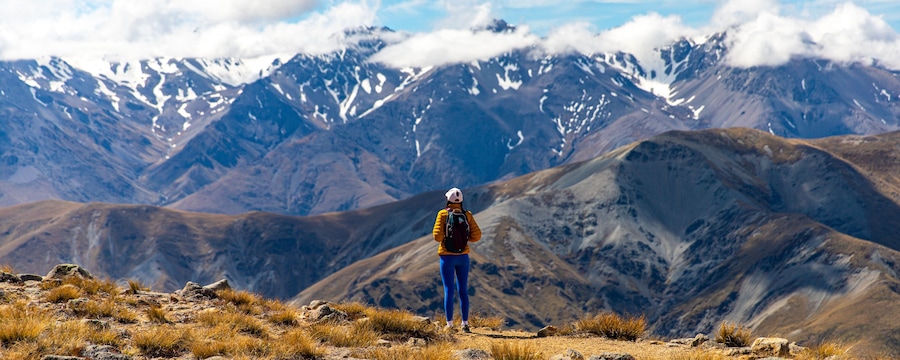 backpacker enjoying the stunning panorama of new zealand alps from the top of mount somers in canterbury