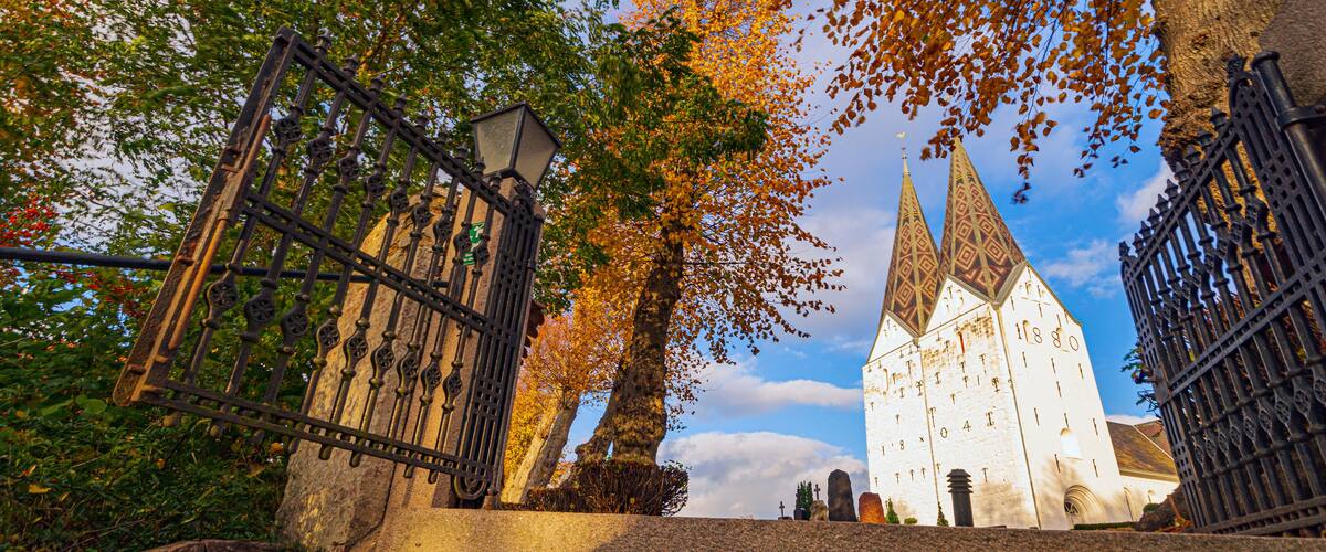 A church with a tall spire and a wrought iron gate.