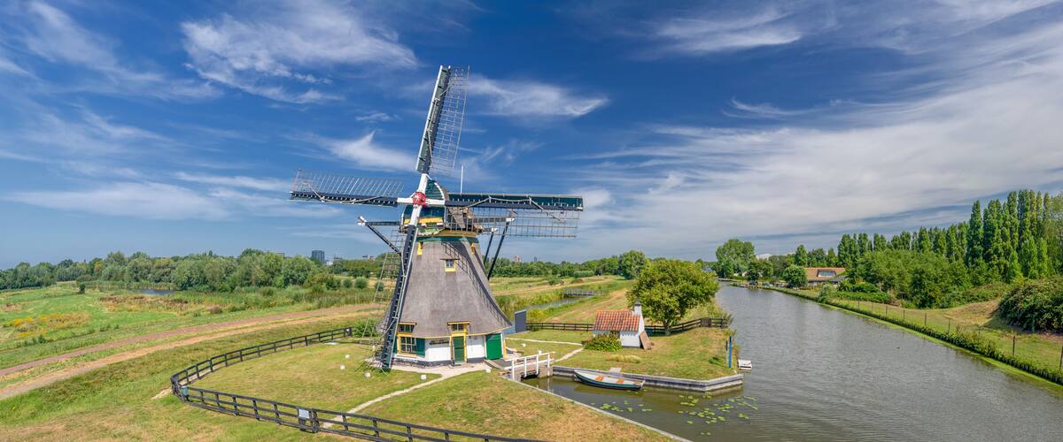 A traditional windmill with a surrounding grassy area and a canal.