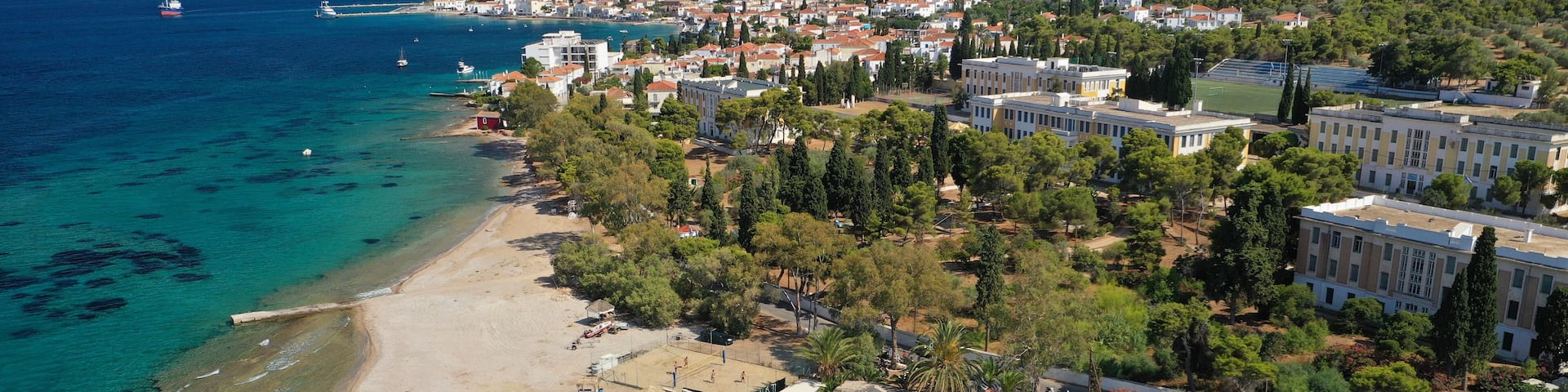 Aerial drone photo of organised with sun beds emerald beach of Kaikia in Ligoneri area near old town of Spetses island, Saronic gulf, Greece