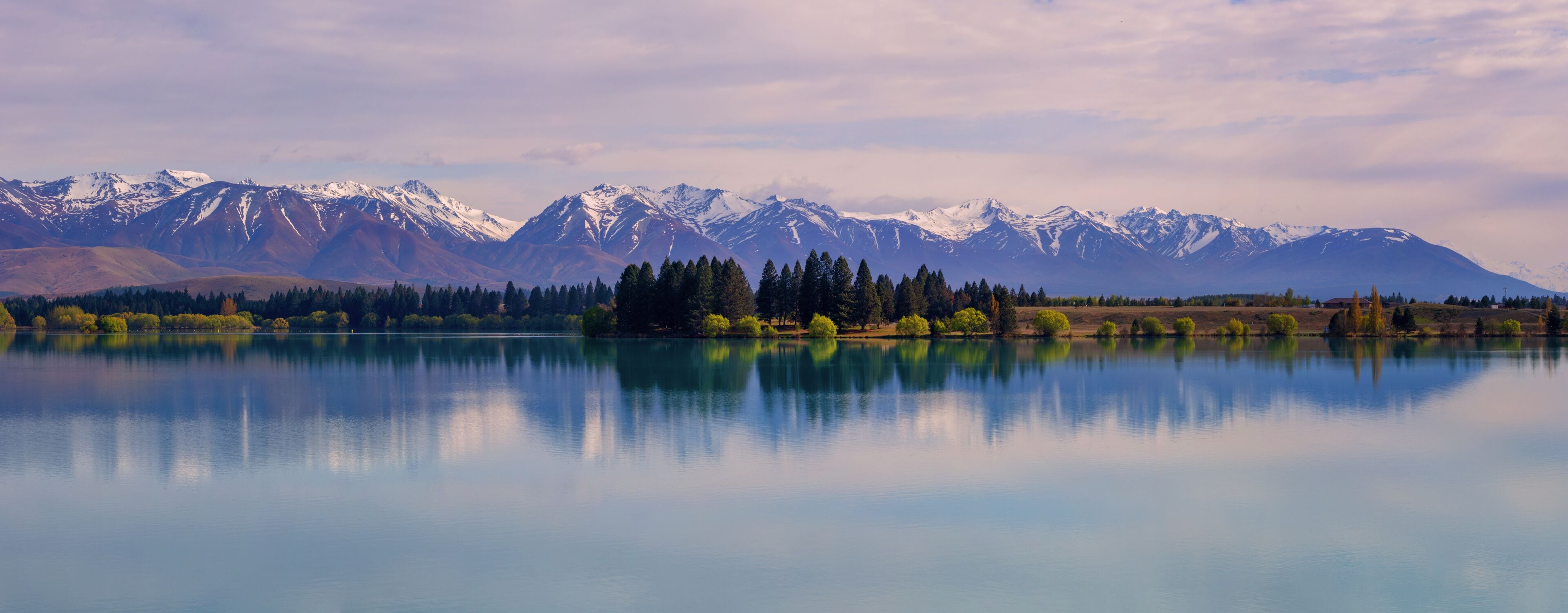 A calm lake reflecting mountains and trees.