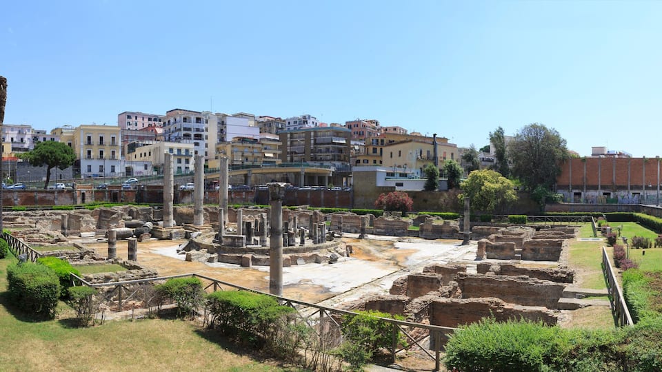 Ancient ruins with a modern cityscape in the background.
