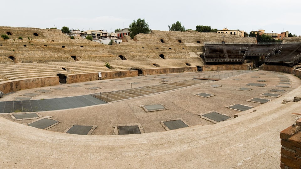 An ancient amphitheater with tiered seating and a central stage.