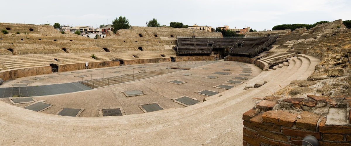 An ancient amphitheater with tiered seating and a central stage.