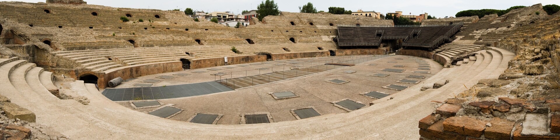 An ancient amphitheater with tiered seating and a central stage.